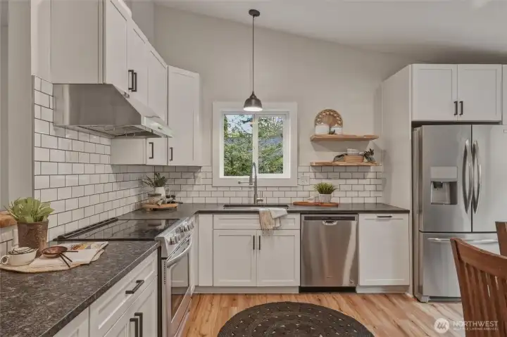 The beautifully updated kitchen showcases honed granite countertops, classic subway tile backsplash, stainless appliances, and crisp white cabinetry. Thoughtful design and abundant natural light make this space both stylish and functional.