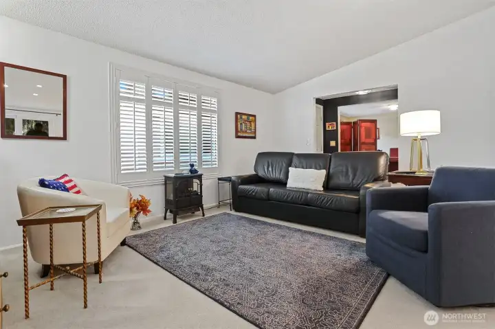 Formal living room with vaulted ceilings opens to the dining room.