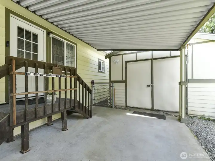 The back entrance to the home from the covered carport area helps protect you from the weather, with a side gate to the back yard area and double door entrance to the large detached shop.