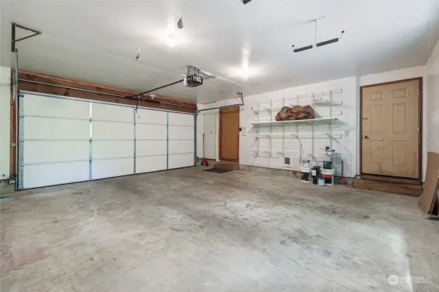 Tidy garage with shelving, window to back, and handy door access to patio/deck.