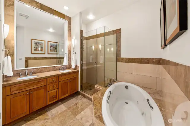 Primary bathroom offers a 5 piece bathroom with the jetted tub.  Toilet has its own room to the left of photo.  Vaulted ceilings throughout this home