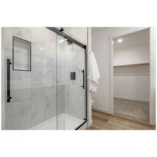 Walk-in primary shower with glass door.