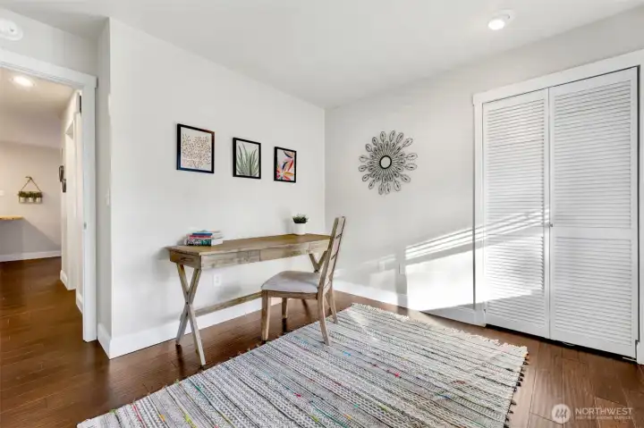 Main level bedroom staged as an office looks out on the covered front porch.