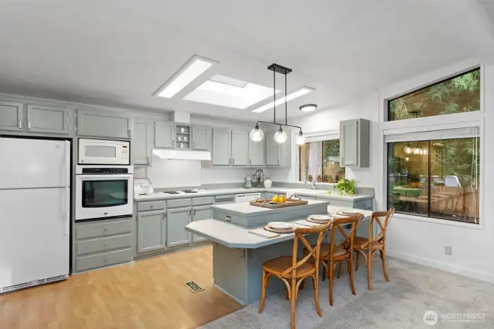 Kitchen is all dressed up with cabinets painted in the latest shade of soothing green, and boasts a spacious breakfast bar.