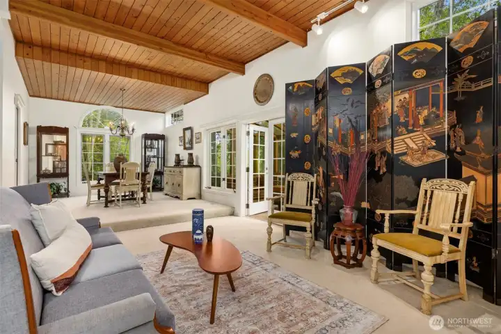 The living room to dining room view showcases the wood deck ceilings and double glass doors that lead to the all season sun room.