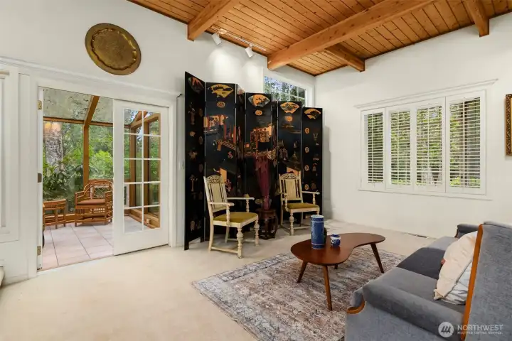 The living room floods with light from the large windows and proximity to the sunroom.