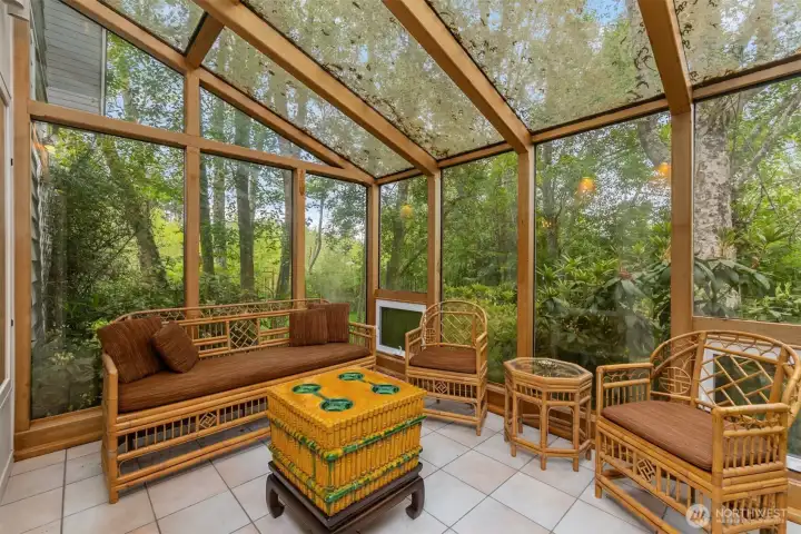The glass sunroom is private and serene surrounded by blooming gardens and mature trees.