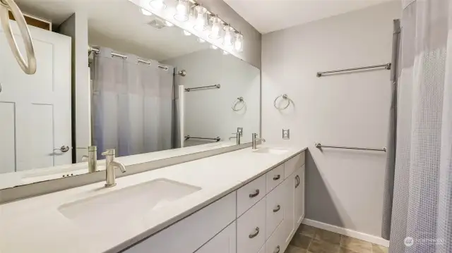 Primary en-suite with a large vanity offering dual sinks, expansive mirror and stylish fixtures.