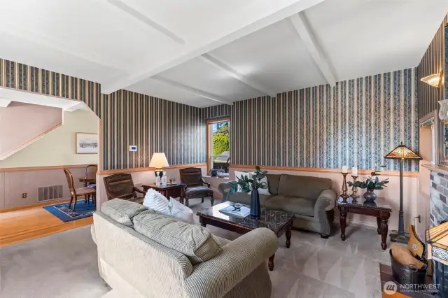 The living room is has a wood- burning fireplace, coffered ceiling, and windows that create a great cross-breeze.