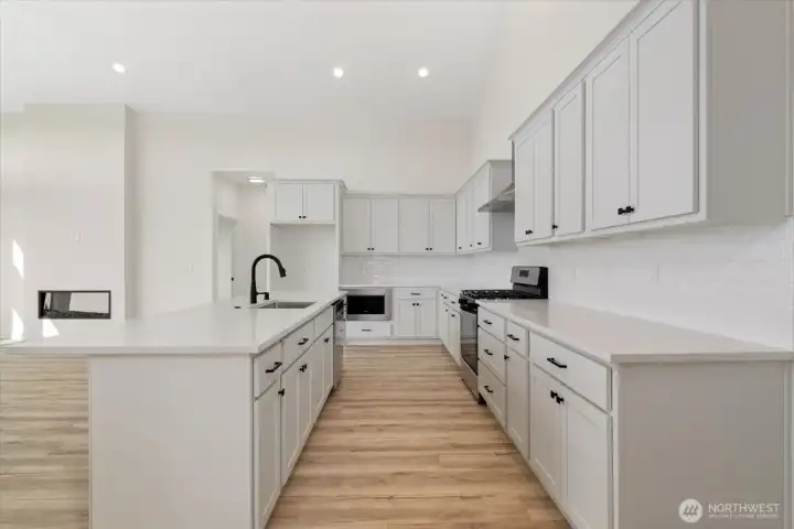 Giant kitchen with custom cabinets and gas range.