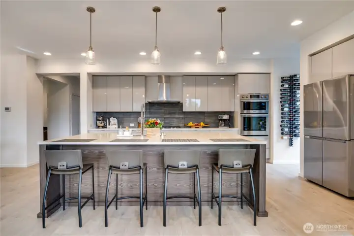 The heart-stopping hub: sleek open kitchen flowing straight into the living room-gas fireplace glowing, quartz island gleaming, everything built to dazzle.