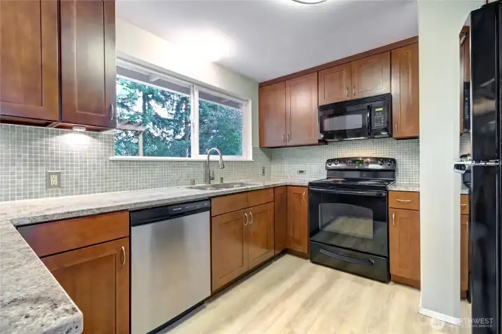 Updated Kitchen w/ white kashmir slab granite countertops & cherry shaker cabinetry.