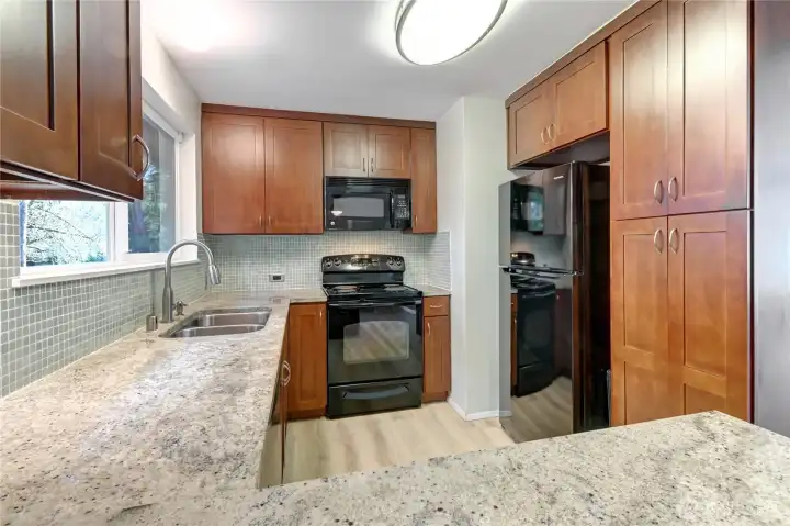 Kashmir white slab granite countertops with tile backsplash, dark cherry custom cabinetry & new lighting.