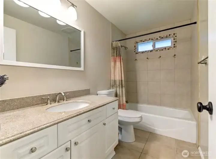 Upper-level Bathroom w/ tile flooring, tile-surround shower, soaker tub, granite vanity & new paint/lighting.