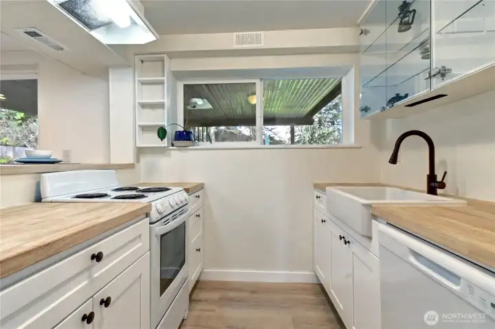 Lower-level kitchen w/ new cabinetry, sink, dishwasher, butcher-block countertops.