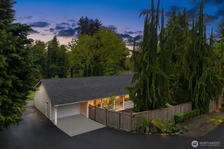 A stunning dusk aerial showcases the property's generous .771 acre lot, mature tree canopy, and excellent street presence, with warm lighting highlighting the home and outbuilding that together make this such a rare and versatile find.