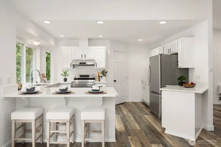 A wider view of the kitchen highlights the thoughtful layout, ample counter space, and seamless flow to the dining area, with bright white cabinetry and bamboo flooring tying the whole space together beautifully.