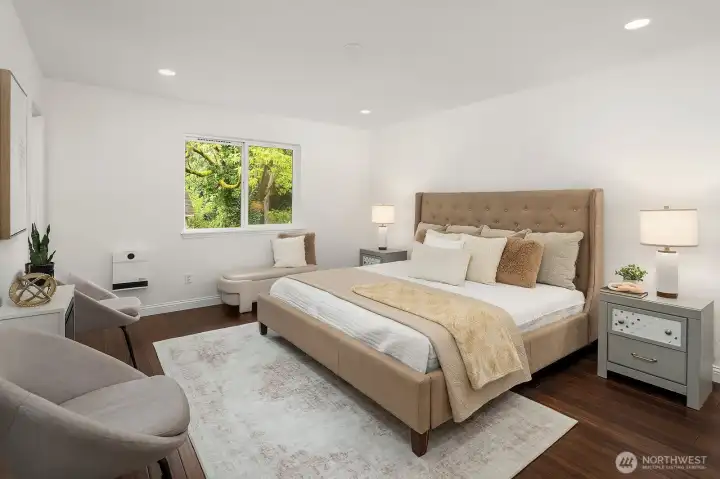 The spacious primary bedroom is a serene retreat, featuring fresh paint, new interior doors, warm bamboo flooring, and a generous window that fills the room with soft natural light and peaceful garden views.