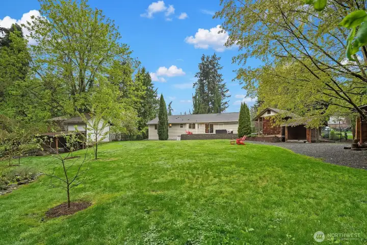This view from the far end of the lot showcases the remarkable depth and privacy of the property, with the home nestled among mature trees and lush greenery — a compelling glimpse at the development potential this expansive .771 acre corner lot offers.