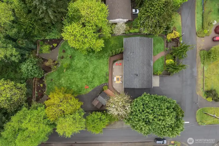 An aerial view highlights the property's impressive tree canopy, generous lot size, and excellent corner position, offering a vivid sense of the endless possibilities this .771 acre parcel presents for development, expansion, or simply enjoying as a private estate.