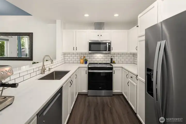 The kitchen has been stylishly updated with quartz counters, bead board, subway tile backsplash, and stainless appliances including a new (2026) convection range. All appliances remain with the home. The kitchen has been stylishly updated with quartz counters, bead board, subway tile backsplash, and stainless appliances including a new (2026) convection range. All appliances remain with the home.