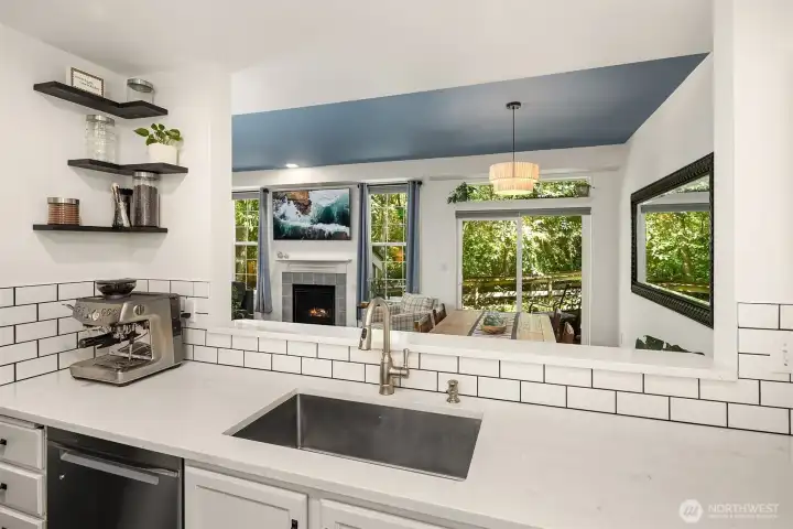 A view looking from the kitchen towards the dining area, living room, and serene outdoor space. A view looking from the kitchen towards the dining area, living room, and serene outdoor space.