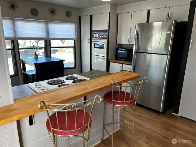 Kitchen has been completely remodeled, with new laminate wood plank flooring, appliances, paint, & fixtures. Breakfast bar with bar stools included.