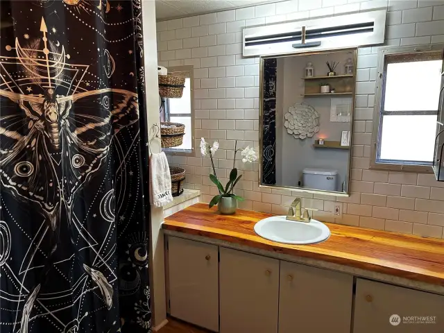 Large bathroom has subway tile backsplash, wood counter, new fixtures, & is light & bright.
