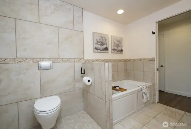 Beyond the deep soaking tub, a wall mounted Toto toilet.  The shower and toilet area have roll in access - no thresholds.  So easy to access and clean!  And beautiful tilework throughout