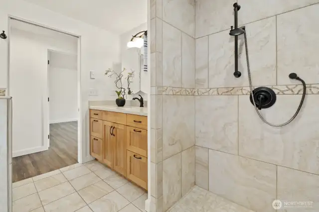 From the shower and vanity, you can see the first bedroom across the hall.