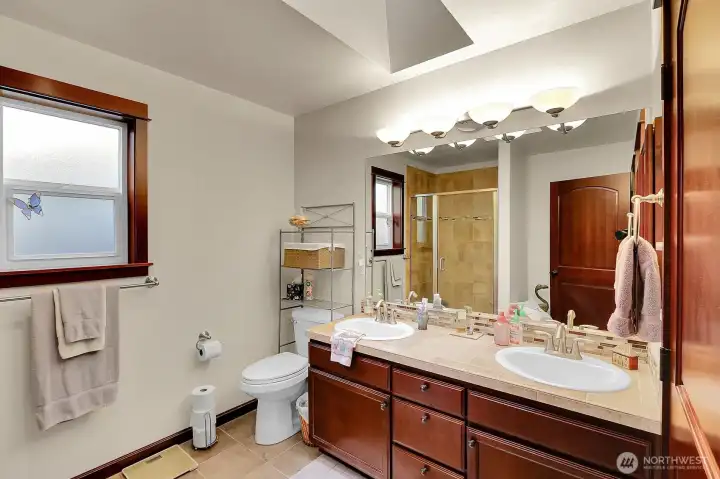 The primary bathroom features double sinks, a spacious shower, and a skylight that fills the space with natural light.