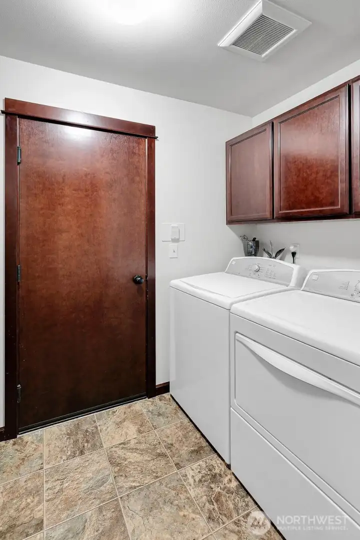 The large laundry room offers ample space for storage, a refrigerator, and convenient access to the two-car garage.