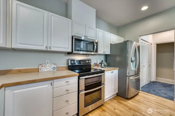 Another view of the kitchen showing the hallway.  Double doors on the left include full size washer and drier.  Coat closet to the right and half bath straight ahead.