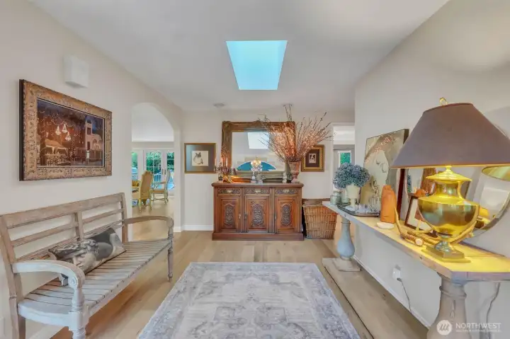 Enter the double doors to the foyer with gleaming, wide plank hardwood floors and skylight.