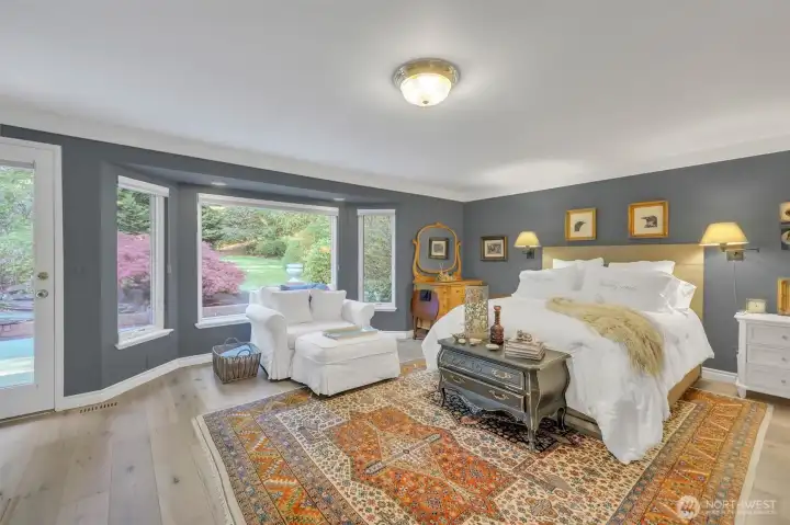 Wide plank, light hardwoods continue into the primary bedroom with sin-filled bay window.