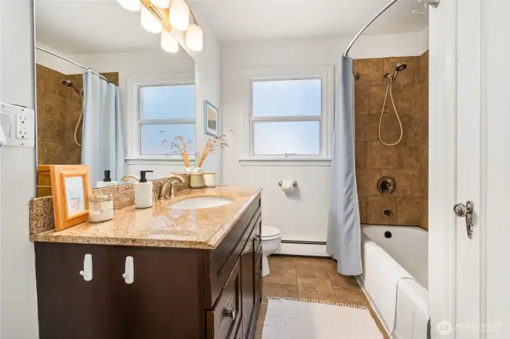 Full bathroom on the main floor with tile floors and tub surround.
