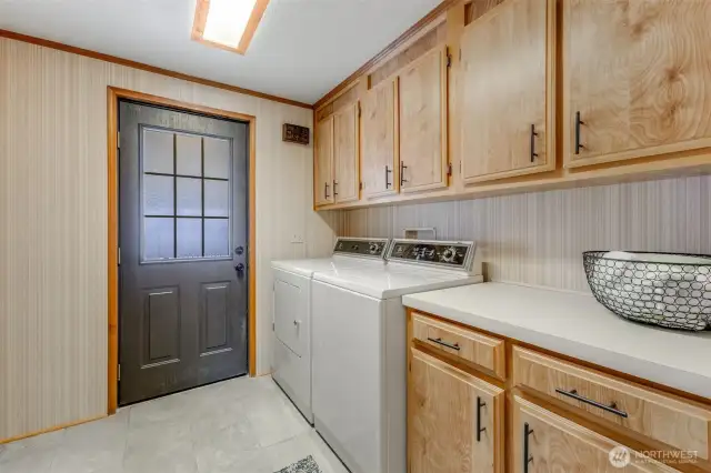 Utility room has tiled floors and features storage, folding counter & washer/dryer convey. Leads to carport & storage shed