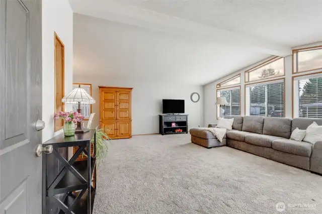Welcome to the open living room with vaulted ceilings, updated windows, 2" faux wood blinds & lots of natural light