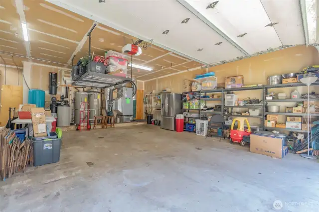 oversize attached garage with drywall, shelving, storage, and the electrical/utility components