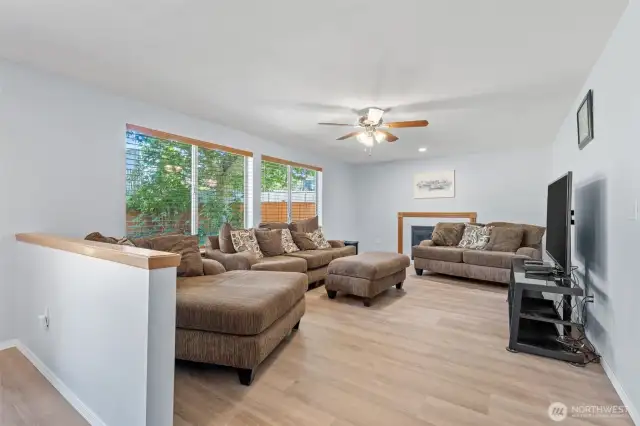Cozy family room with fireplace, ceiling fan and wall of windows.