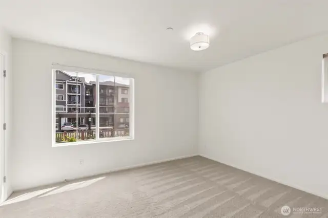 The primary bedroom offers a spacious, light-filled retreat with room to unwind—designed for comfort, style, and restful living.