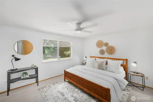 The primary bedroom features views of the yard behind the house and an attached en-suite bathroom.