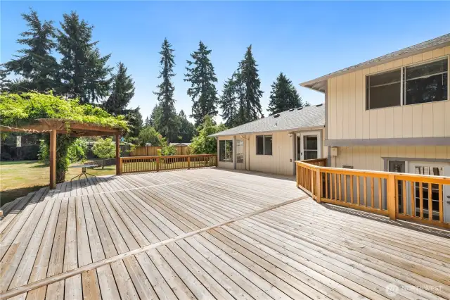 Spacious deck, wonderful outdoor living space, charming and well-established wisteria tree, decorative arbor, wrap-around stairs. This area is perfect for relaxing and entertaining, offering a beautiful and inviting outdoor environment.