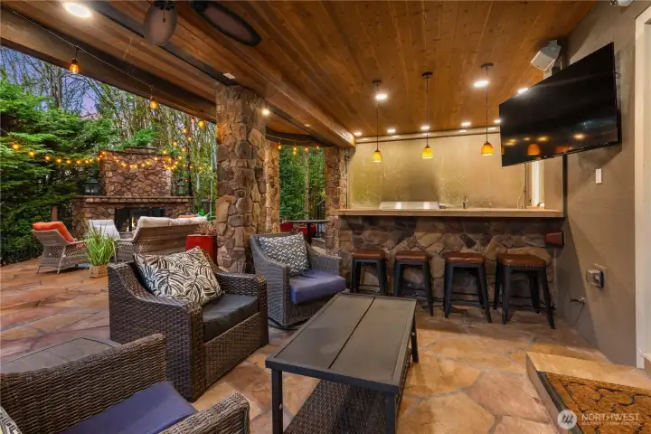 Another view shows multiple seating options. The TV and ceiling fan, plus the wood ceiling and speakers make this perfect for year round enjoyment.