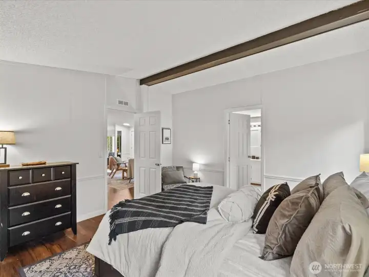Primary bedroom with vaulted ceiling with wood beam.