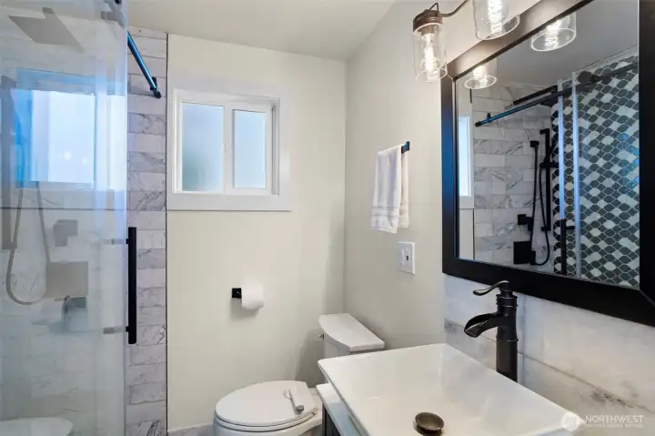 A marble-clad 3/4 bathroom, discreetly positioned on the main level to offer both high-end utility and the convenience of a guest powder room.