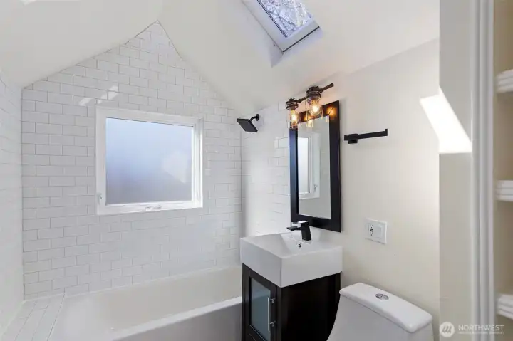 The upper level bathroom celebrates indoor-outdoor synergy, where the vaulted ceilings and natural light-wells merge the interior with the elements.