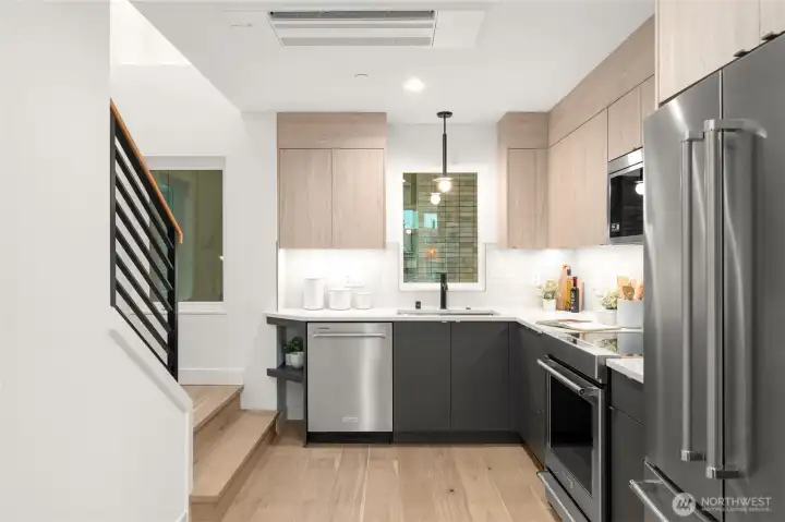 Chef’s kitchen with sleek quartz countertops and brand-new stainless steel appliances.