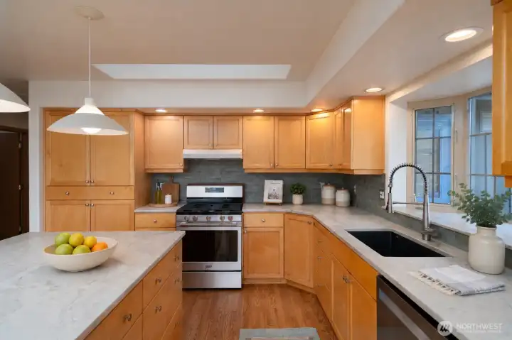 Bright kitchen with quartz counters, skylight, and gas range. Bright kitchen with quartz counters, skylight, and gas range.