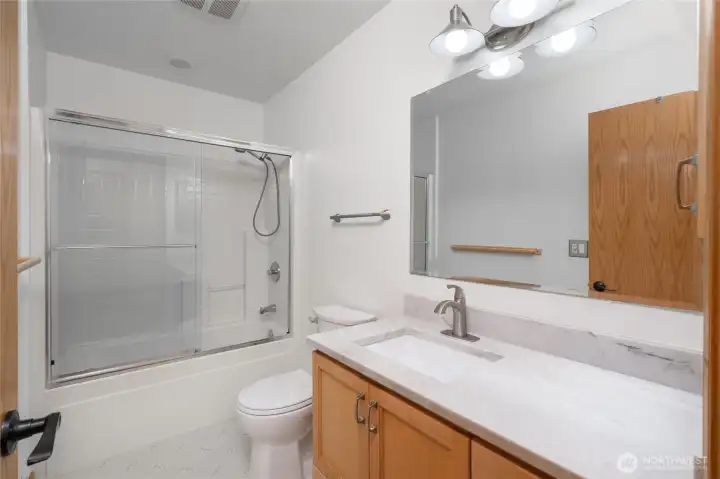 Updated bath with quartz vanity and sleek glass-enclosed shower. Updated bath with quartz vanity and sleek glass-enclosed shower.